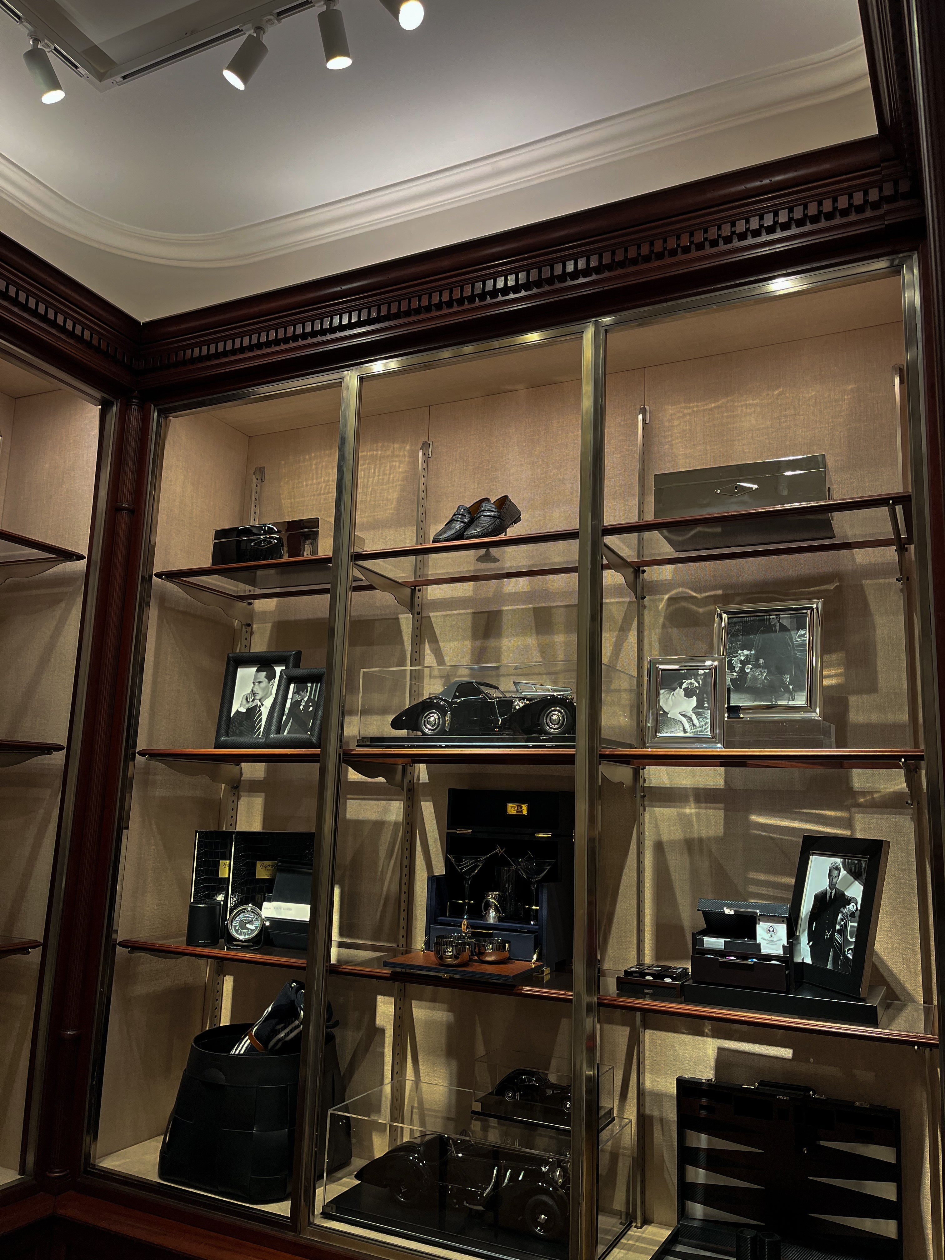 Display case in a store in Paris with framed pictures and objects in a room with wooden paneling.