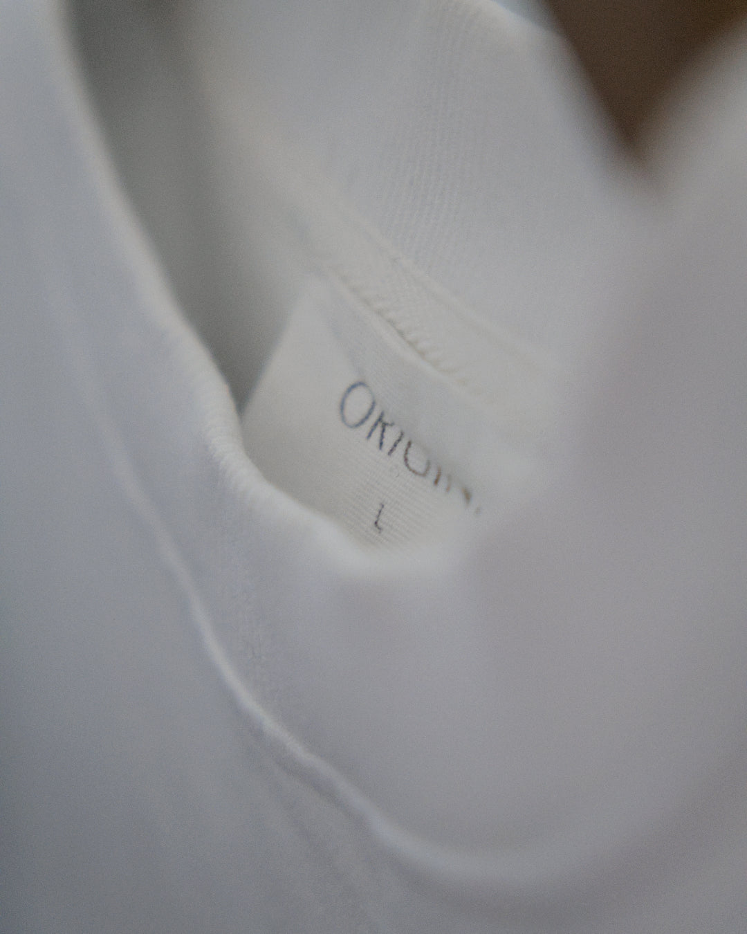 Neck detail white Origin. tee, featuring ribbed collar, herringbone neck tape and organic cotton fabric with branded label.