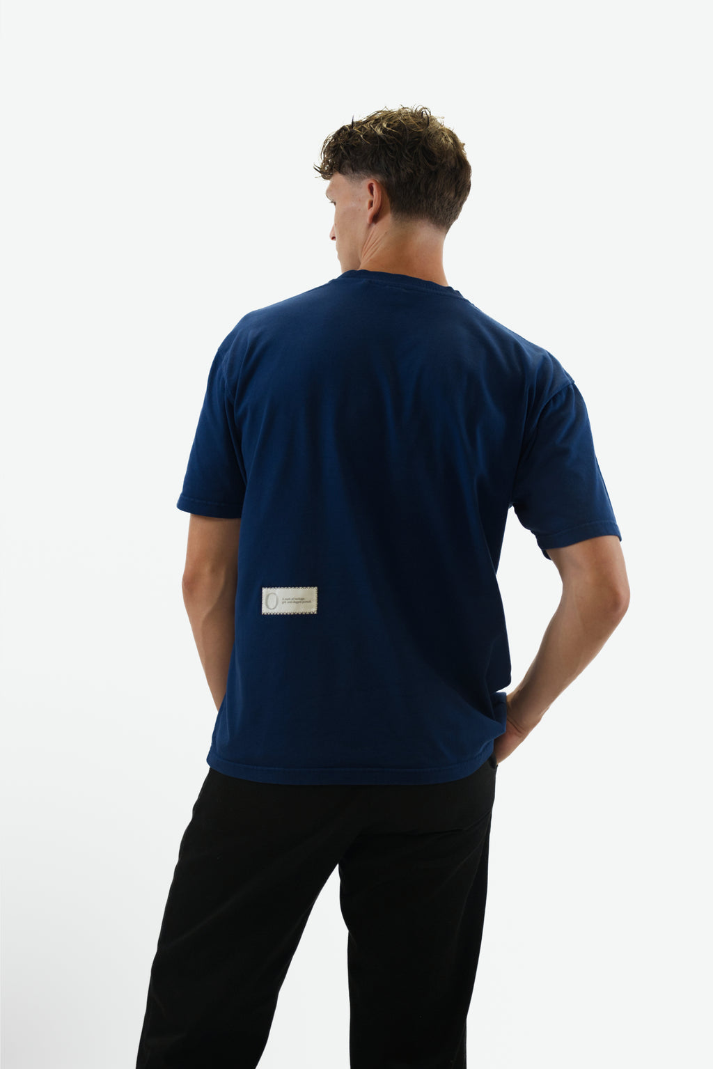 Back view of model wearing the Foundation Tee in indigo blue from Origin. made from organic cotton in a clean studio setting.