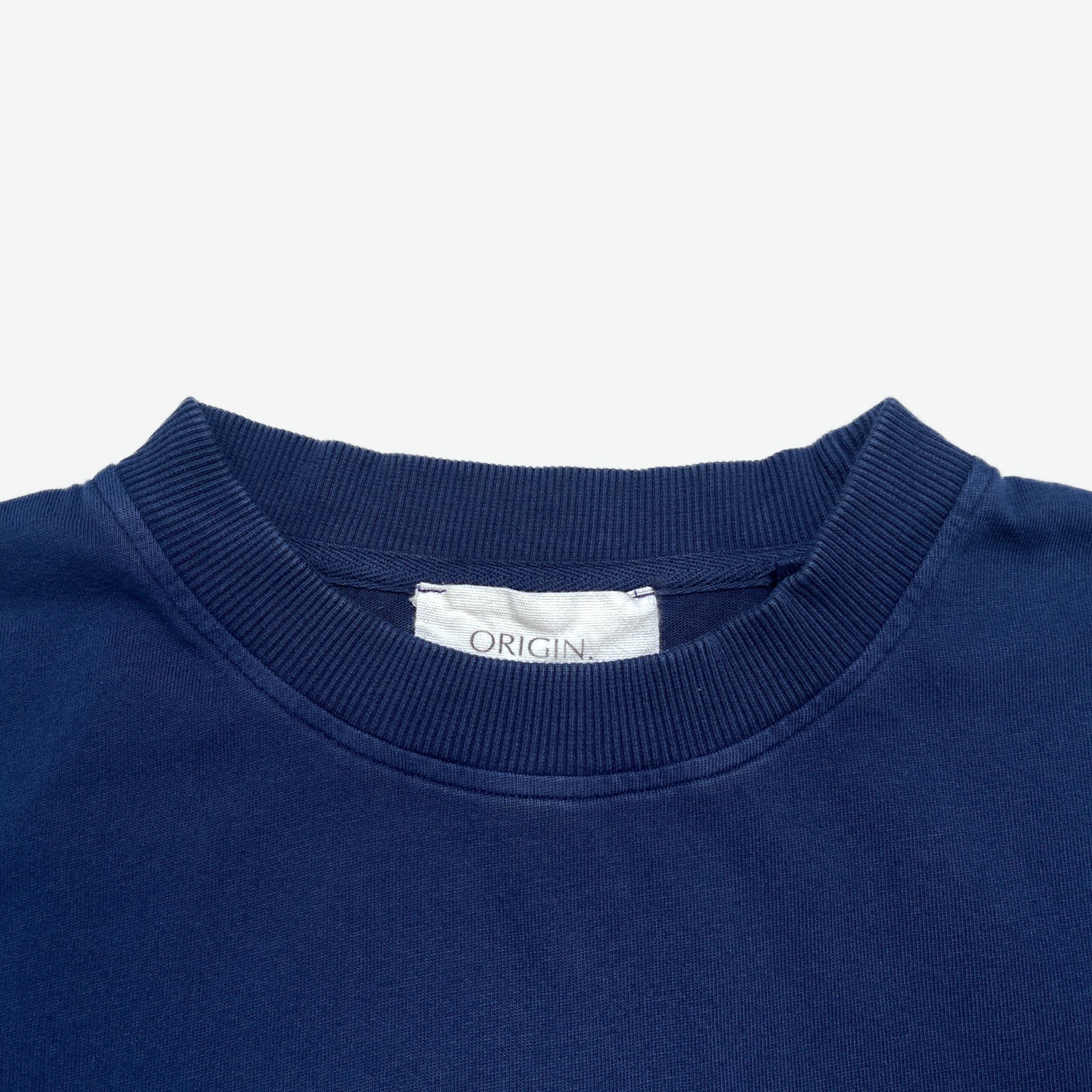 Neck detail Foundation Tee Origin. in indigo blue, featuring ribbed collar and organic cotton fabric with branded label.