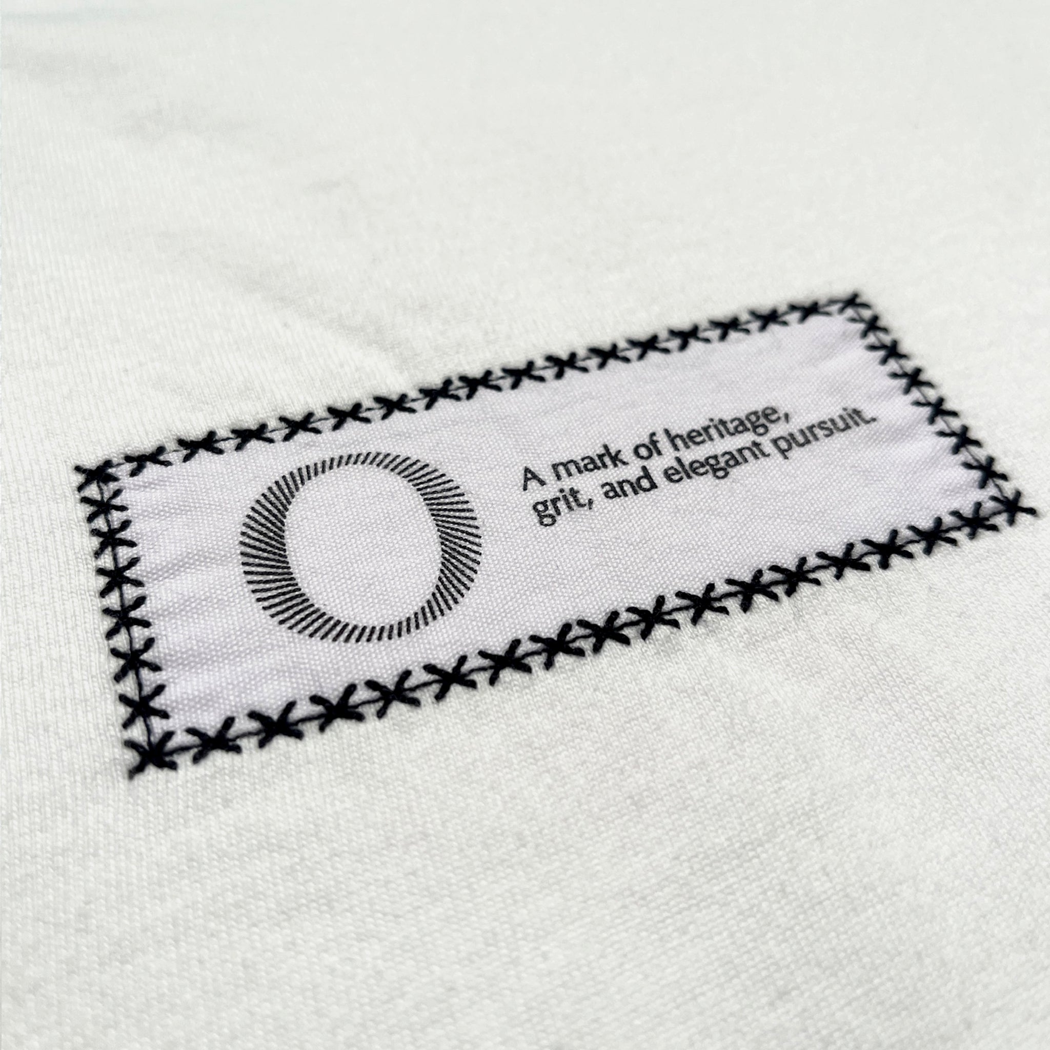 Back detail of the Foundation Tee Origin. in white, featuring back embroidered statement patch on organic cotton fabric.
