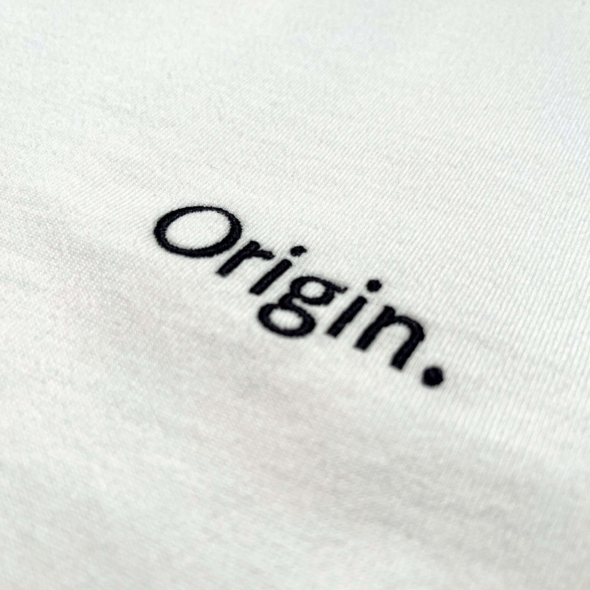 Front detail of Foundation Tee Origin. in white, featuring embroidery on organic cotton fabric.