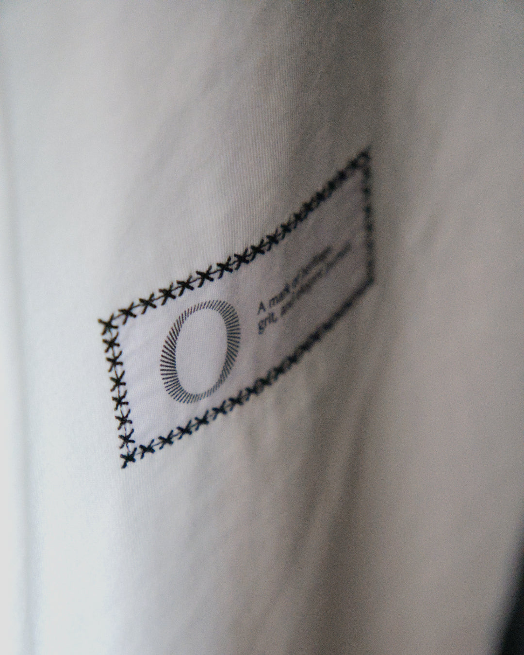 Side view back detail of the Foundation Tee Origin. in white, featuring back embroidered statement patch on organic cotton fabric.