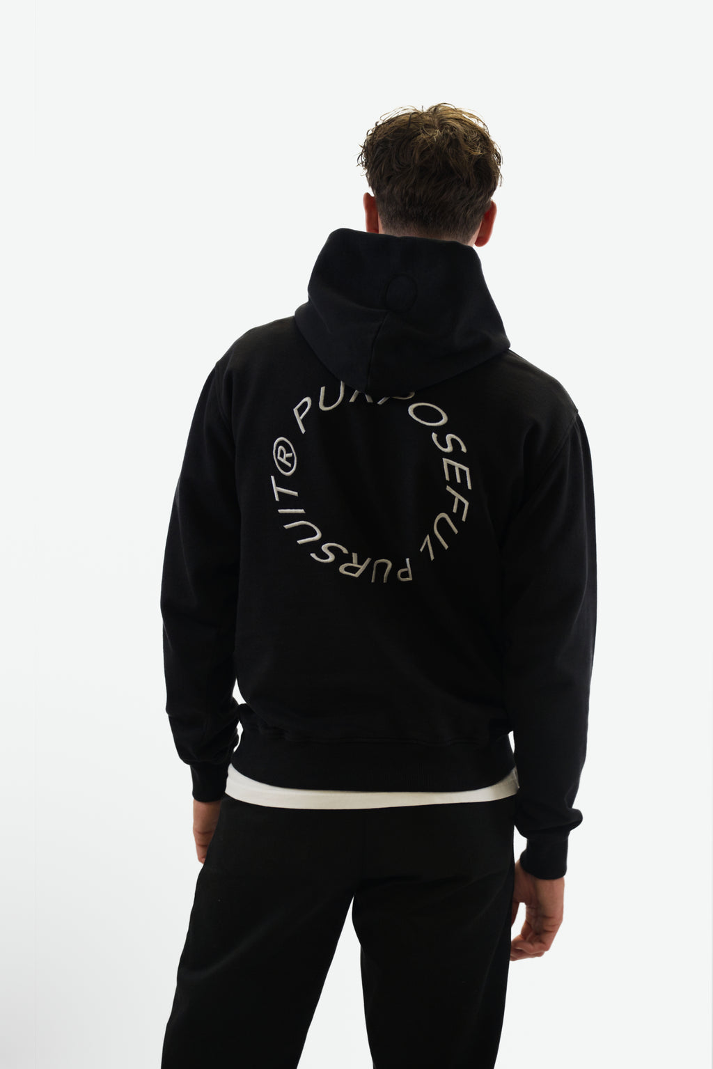 Back view of model wearing the Prelude Hoodie in black from Origin. made from organic cotton in a clean studio setting.