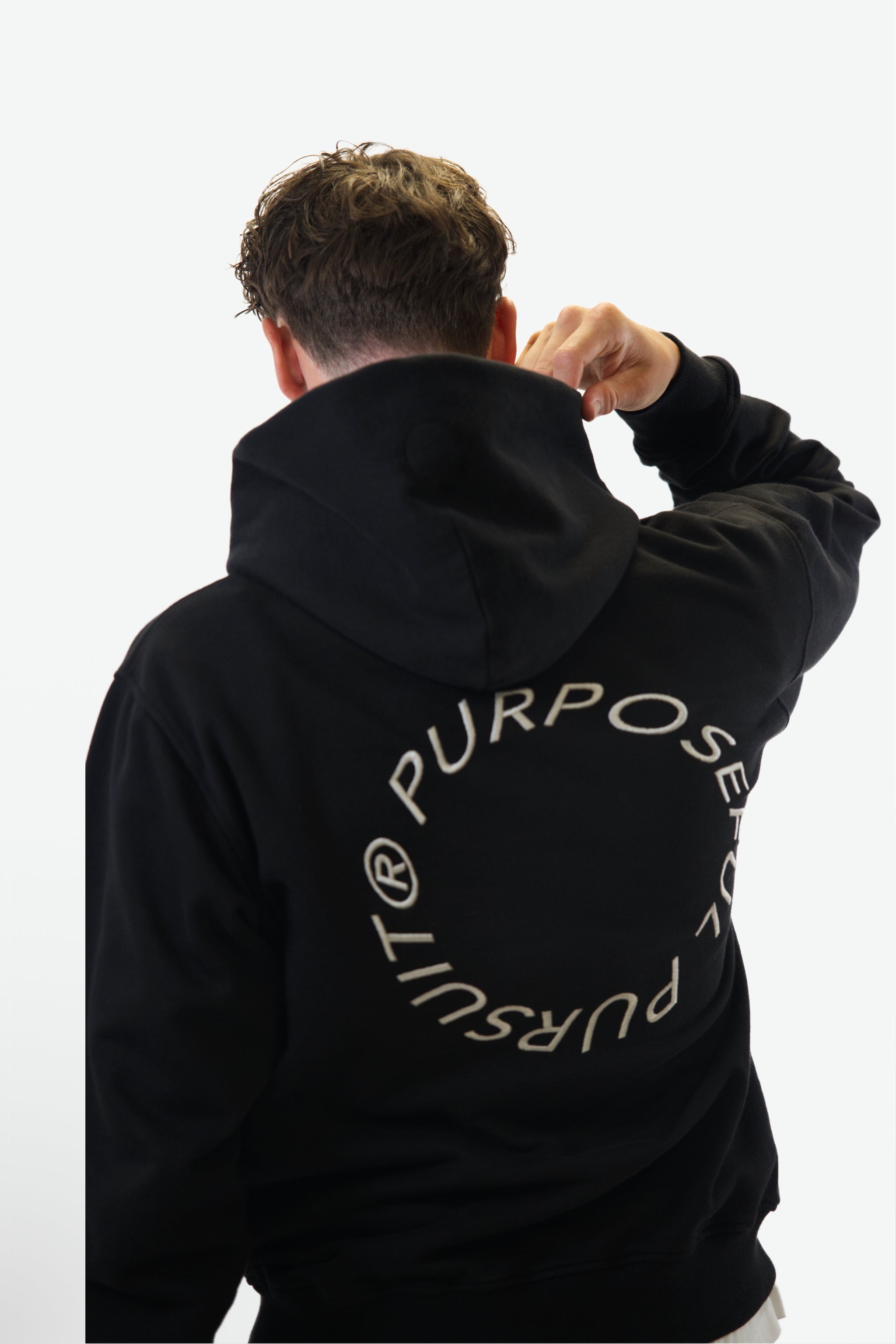 Back view close-up of model wearing the Prelude Hoodie in black from Origin. made from organic cotton in a clean studio setting.