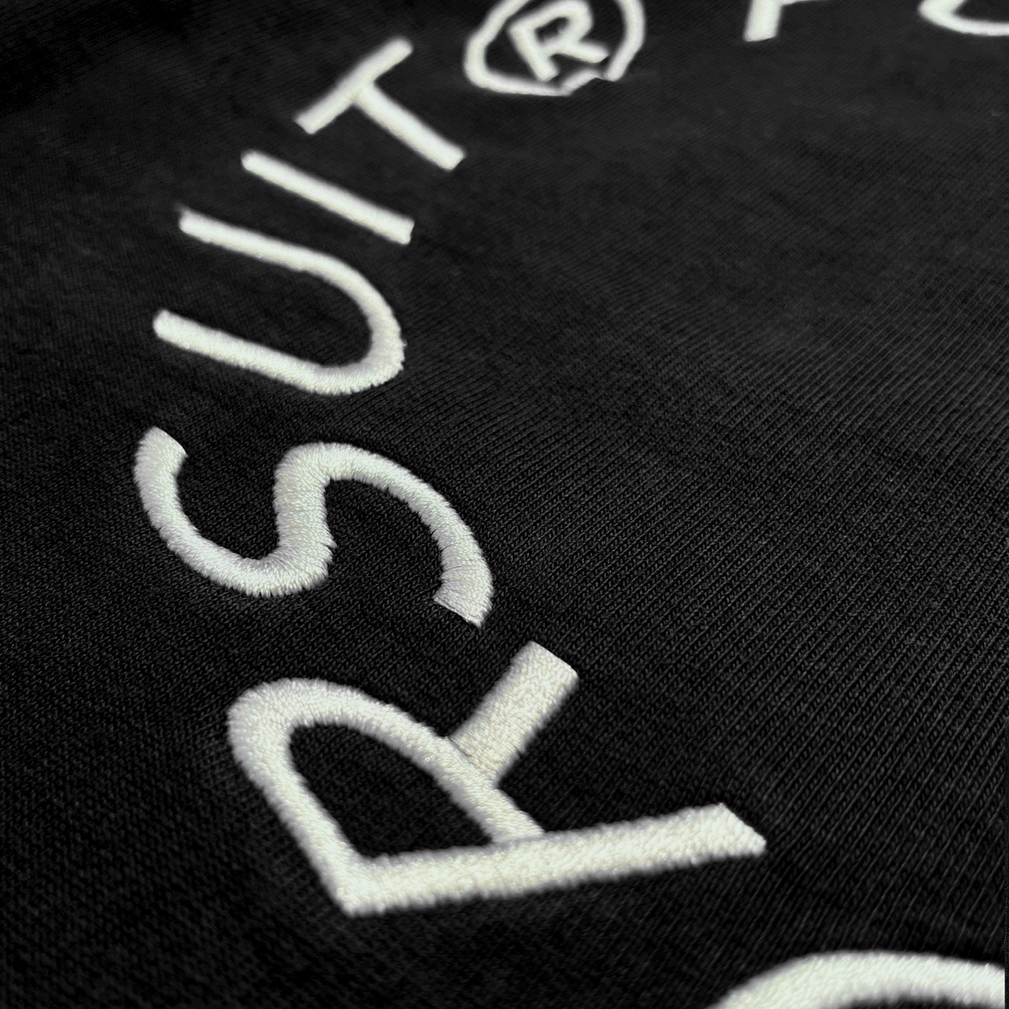 Back detail of Prelude Hoodie Origin. in black, featuring embroidery on organic cotton fabric.