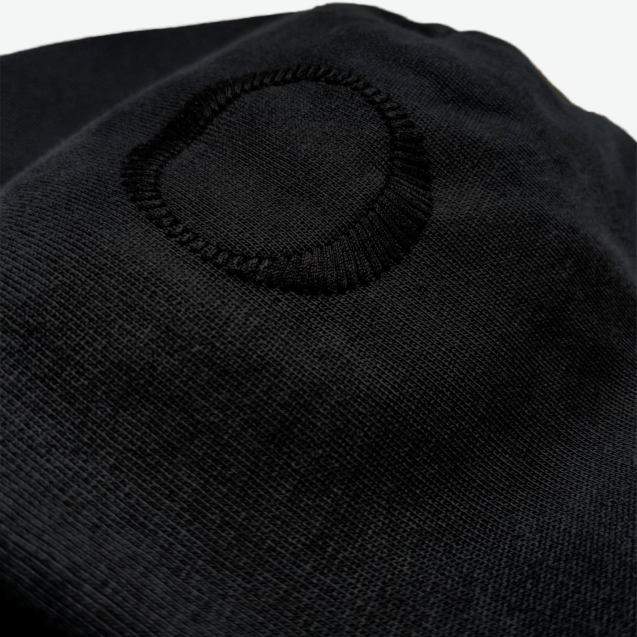 Hood detail of the Prelude Hoodie Origin. in black, featuring hood embroidery from Origin. Slash Logo on organic cotton fabric.