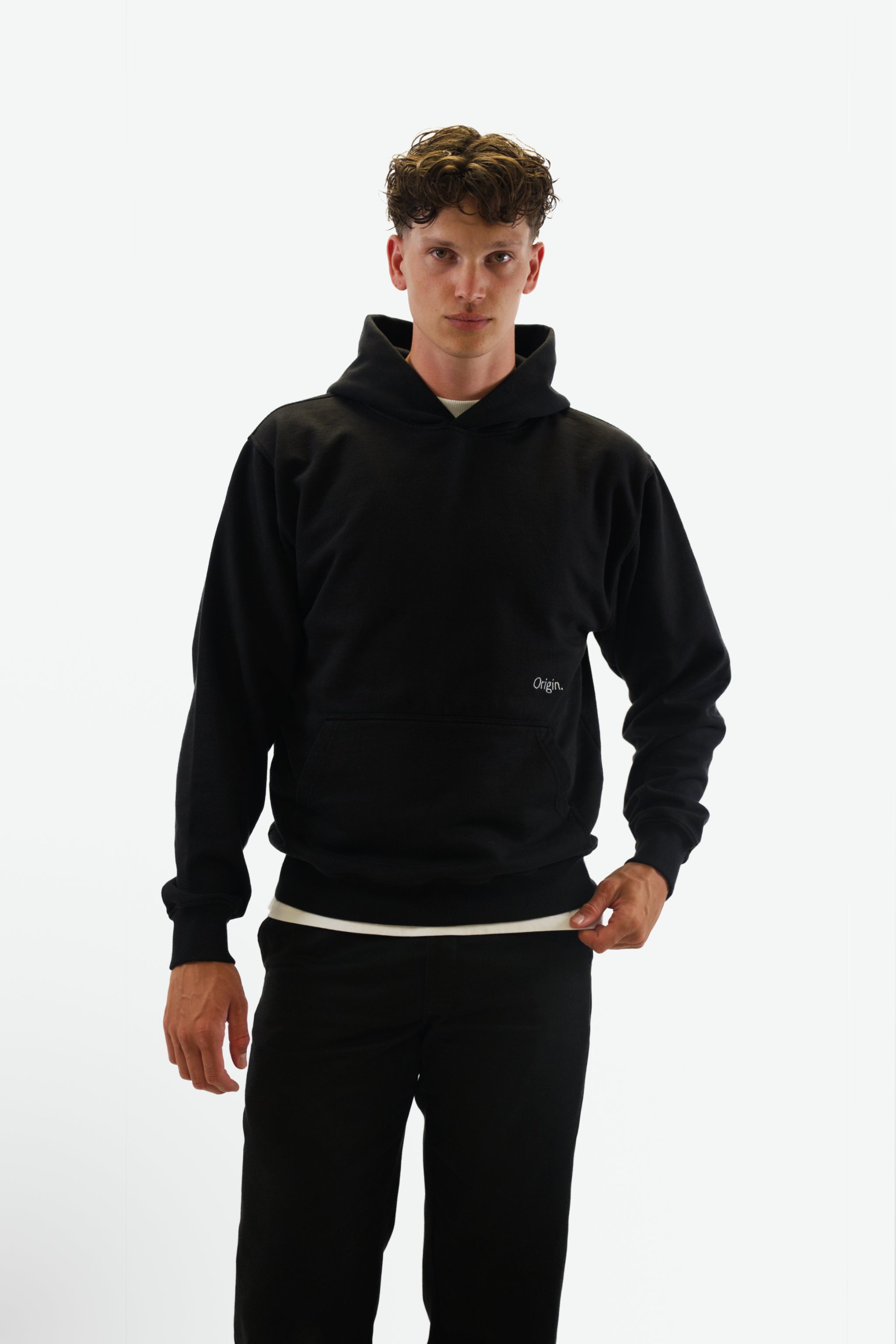 Front view of model wearing the Prelude Hoodie in black from Origin. made from organic cotton in a clean studio setting.