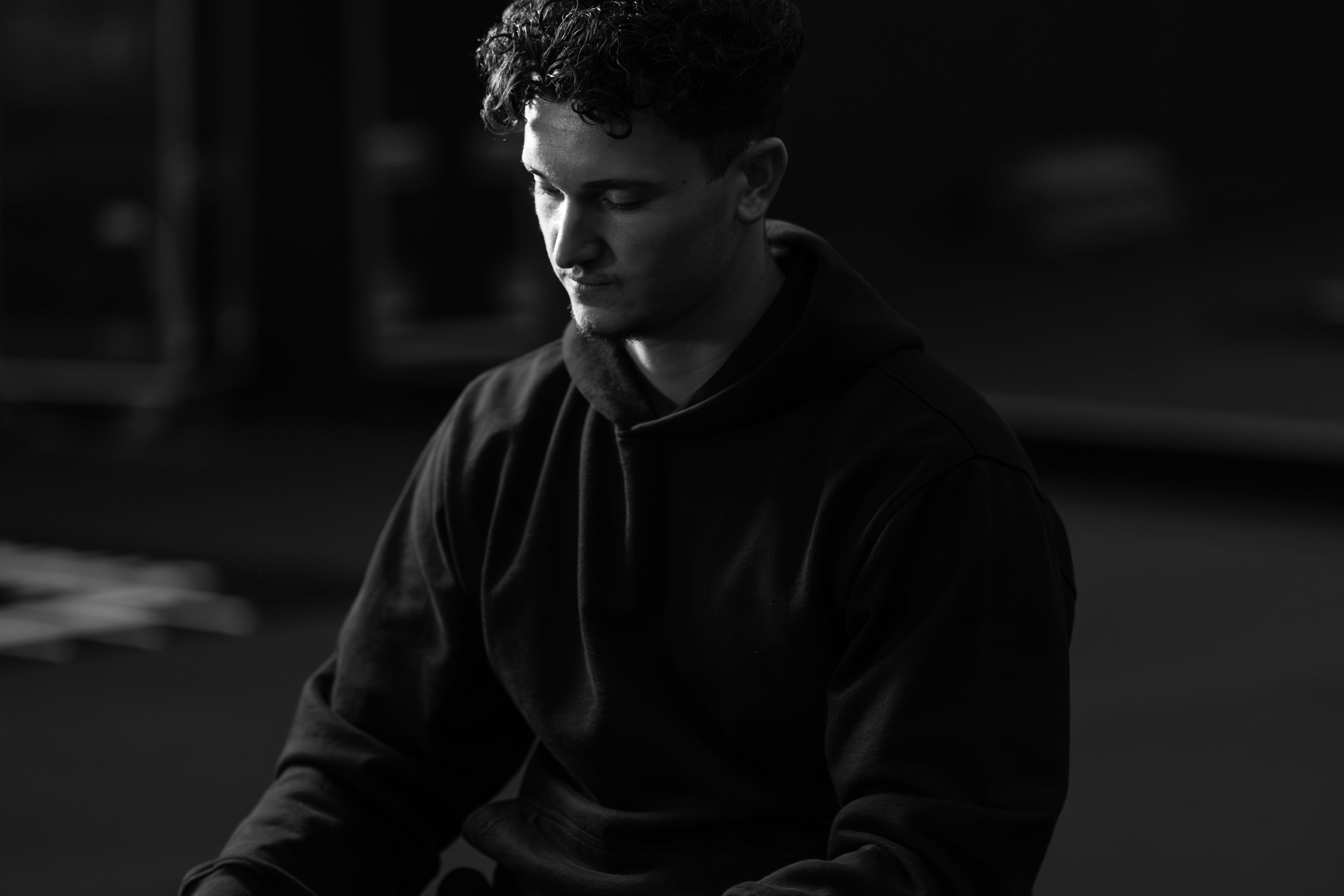 Model wearing the Prelude Hoodie Black from Origin. and is sitting in a gym.