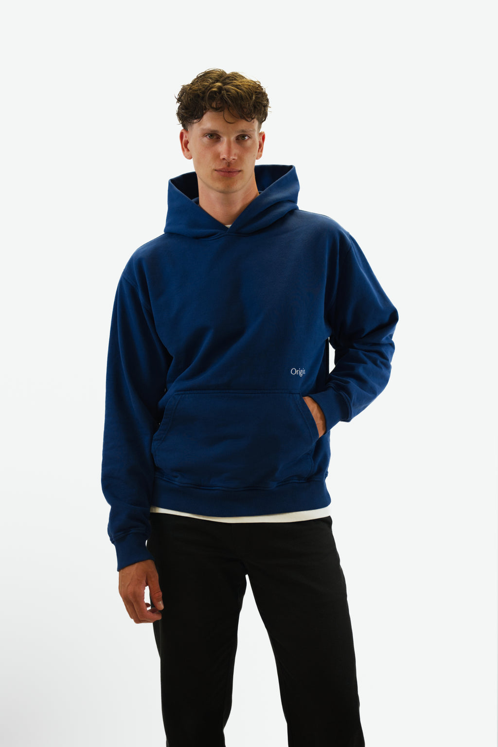 Front view hand in pocket of model wearing the Foundation Tee in indigo blue from Origin. made from organic cotton in a clean studio setting.