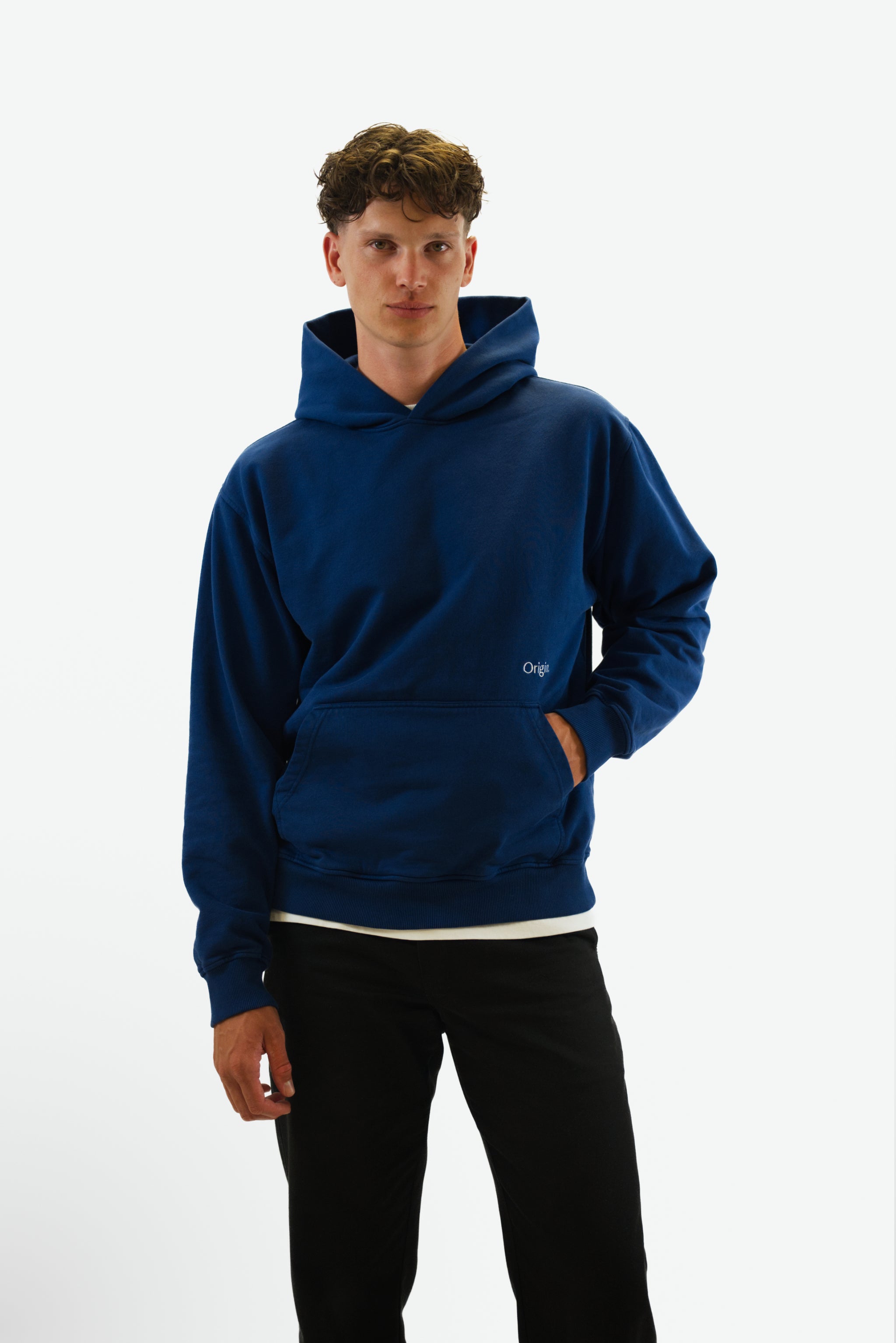 Front view hand in pocket of model wearing the Foundation Tee in indigo blue from Origin. made from organic cotton in a clean studio setting.