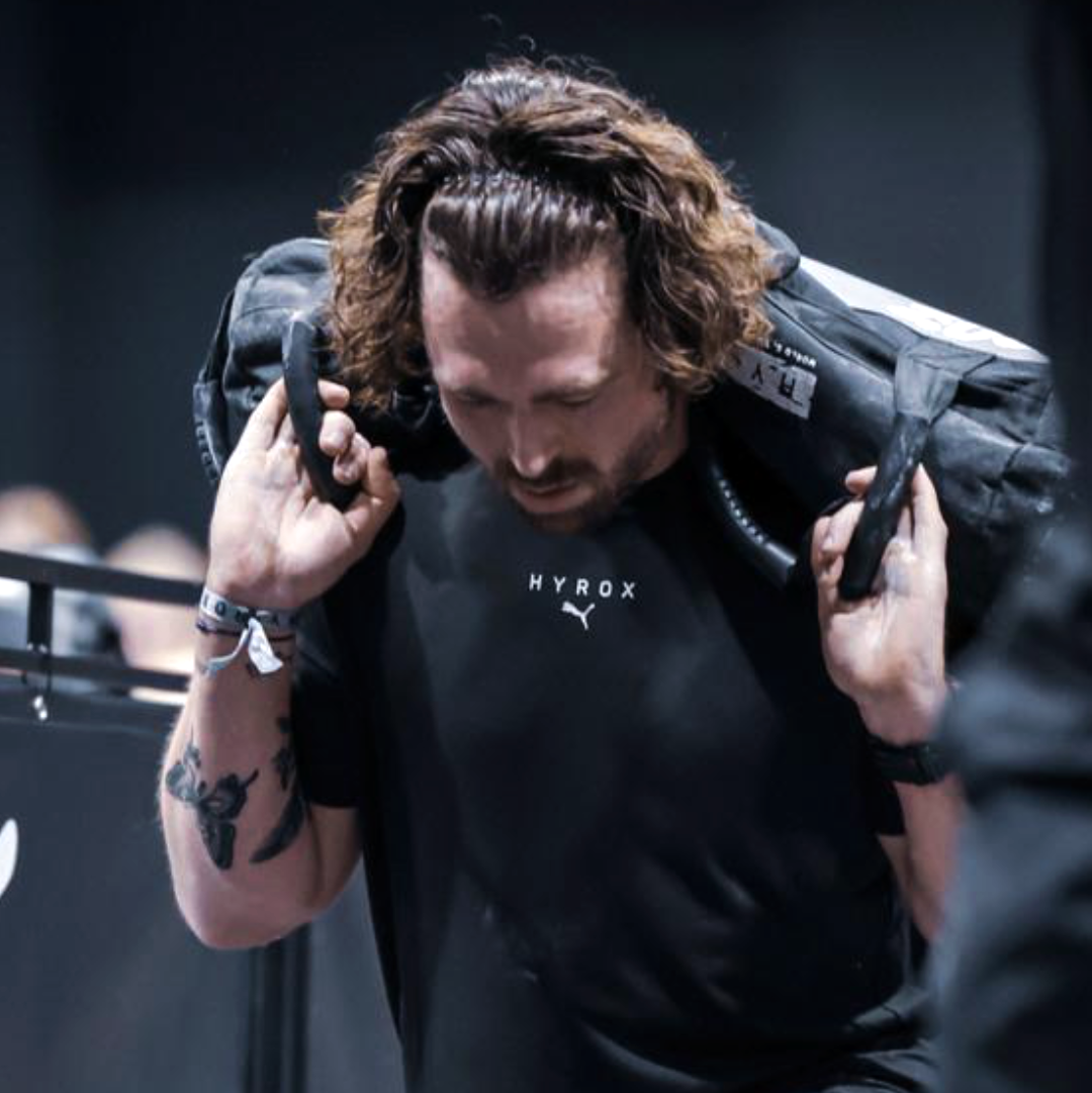 Martijn carrying a sandbag during a Hyrox game.