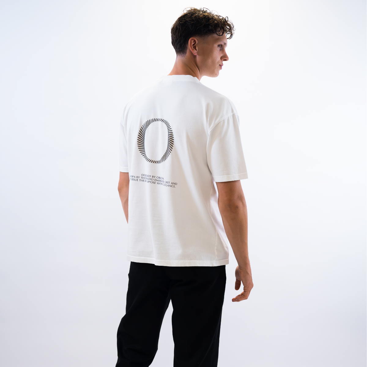 Model wearing The Slash Tee Origin. in white during a model shoot in a clean studio setting.