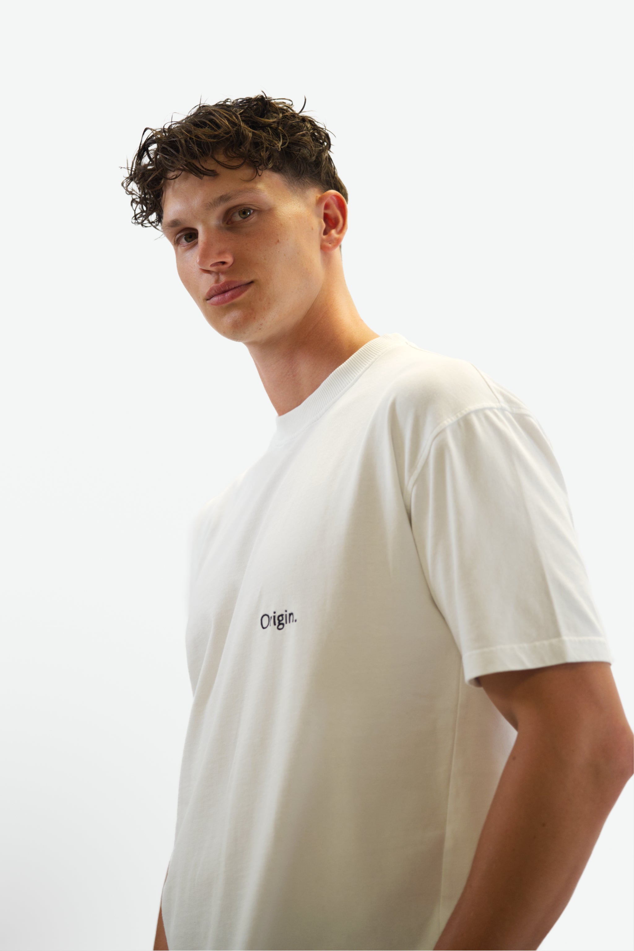 Front view close-up of model wearing The Slash Tee in white from Origin. made from organic cotton in a clean studio setting.