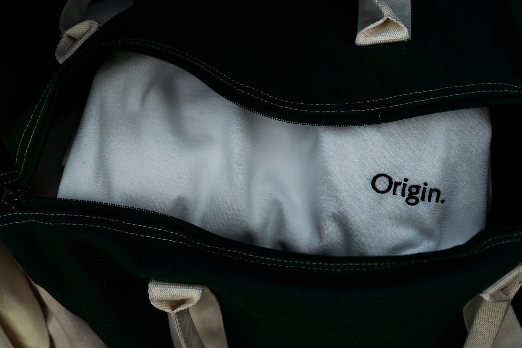Front view white Origin. organic cotton tee folded in a sports bag.